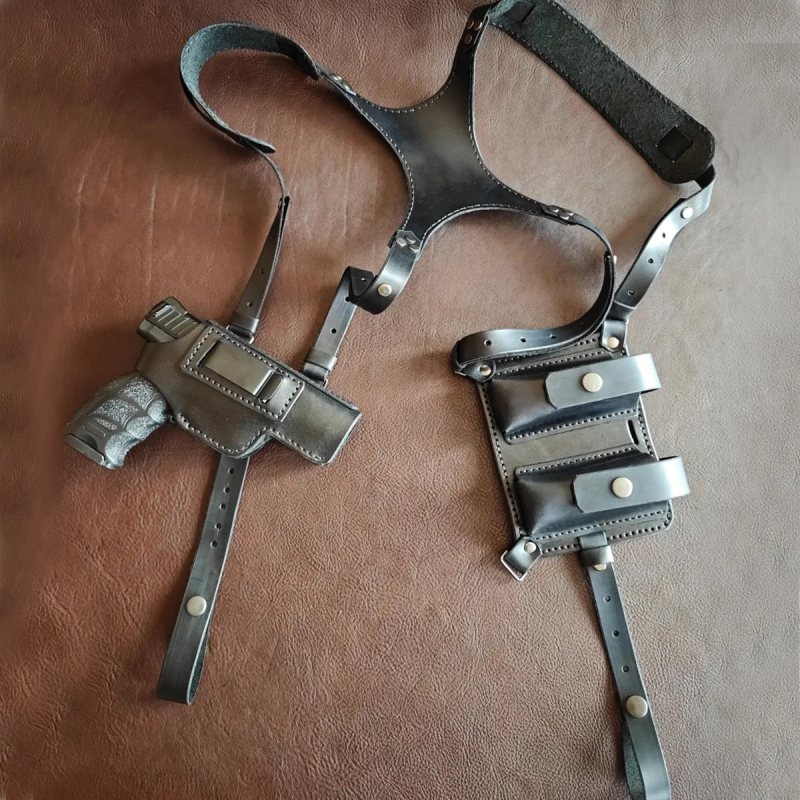 Black leather shoulder holster set with holster and dual magazine pouches laid flat on brown surface