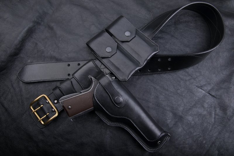 Black leather drop leg holster set with matching belt and pouch on black background