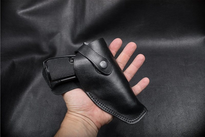 Black Leather Field Guard Holster held in hand with pistol inserted showing snap strap closure