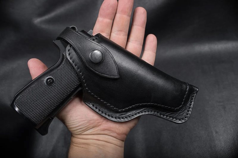 Black Leather Flap OWB Compact Hunting Holster held in hand with pistol inserted showing snap retention strap