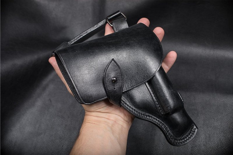 Black Leather Scout Utility Holster held in hand showing covered flap design and attached side pouch