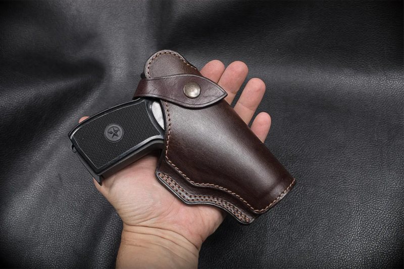 Brown Leather Field Guard Holster held in hand with pistol inserted showing covered front and snap strap