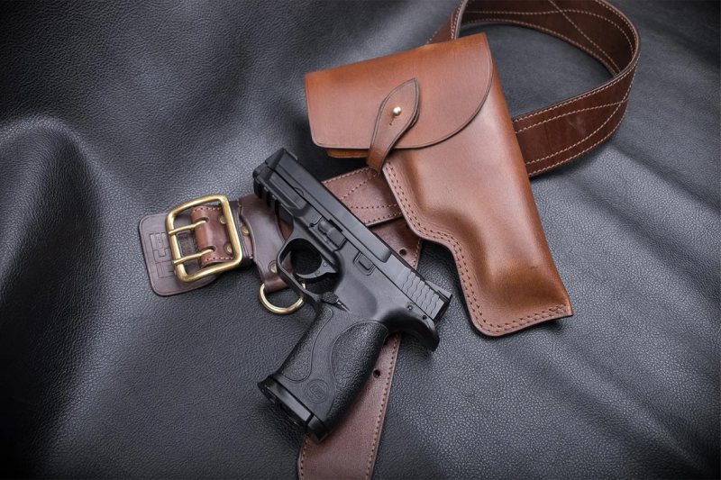 displayed with matching leather belt and handgun on black leather surface