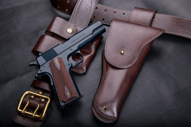 Brown leather vintage belt holster set with matching pouch and pistol on black background