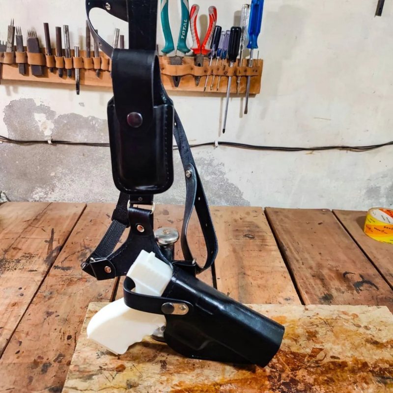 Leather chest holster displayed on workbench showing holster body and harness assembly