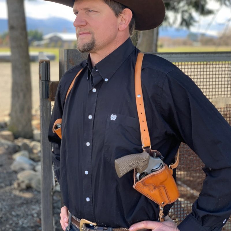 Custom brown leather vertical shoulder holster worn under western shirt with adjustable harness